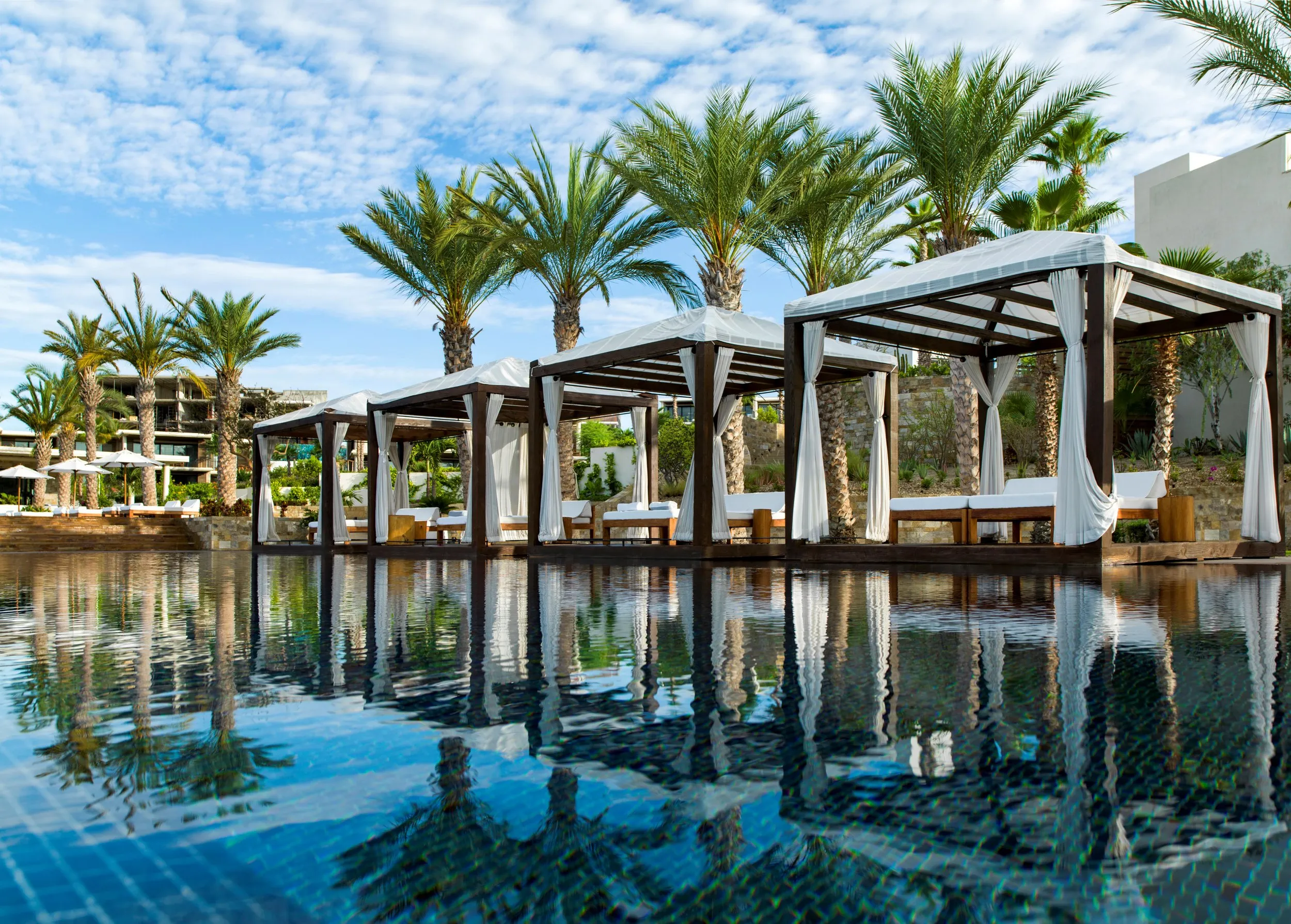 Luxury pool area with cabanas and palm trees